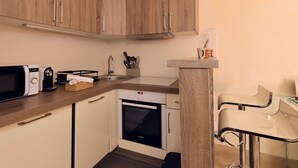 A compact kitchen with wooden cabinets, a Bosch oven, a microwave, and a small bar stool. - Renovated studio in Courchevel 1850, ski-in/ski-out, 4 pax, parking included (Courchevel)