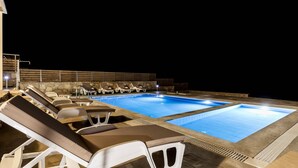 Une piscine extérieure avec des chaises longues et un mur en pierre.