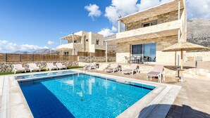 Une piscine avec des chaises longues, une pergola et une vue sur les montagnes.