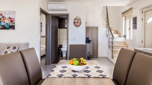 Un salon moderne comprenant une table à manger, un canapé, un escalier et donnant sur la cuisine.