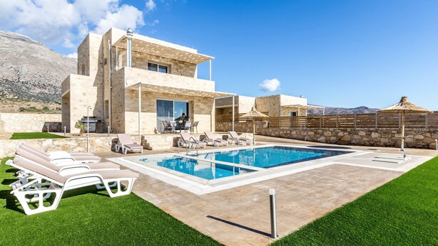Une villa moderne dotée d’une piscine, d’un espace extérieur aménagé et offrant une vue sur les montagnes.