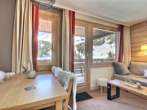 Ein gemütliches Zimmer mit einem Holztisch, einer Couch und einem Fenster mit Blick auf Schnee.