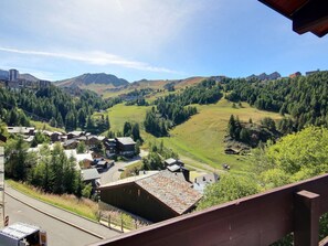 Eine gebirgige Landschaft mit einem Dorf, Häusern mit geneigten Dächern und einer Straße.