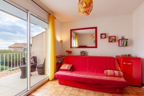 Een rode bank, een rode kast, een spiegel en een balkon met uitzicht.