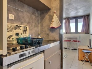 A compact kitchen with a stove, sink, and a small refrigerator. There is a dining area with a table and chairs. - Studio for 2 at the foot of the slopes, Plagne Centre (La Plagne)
