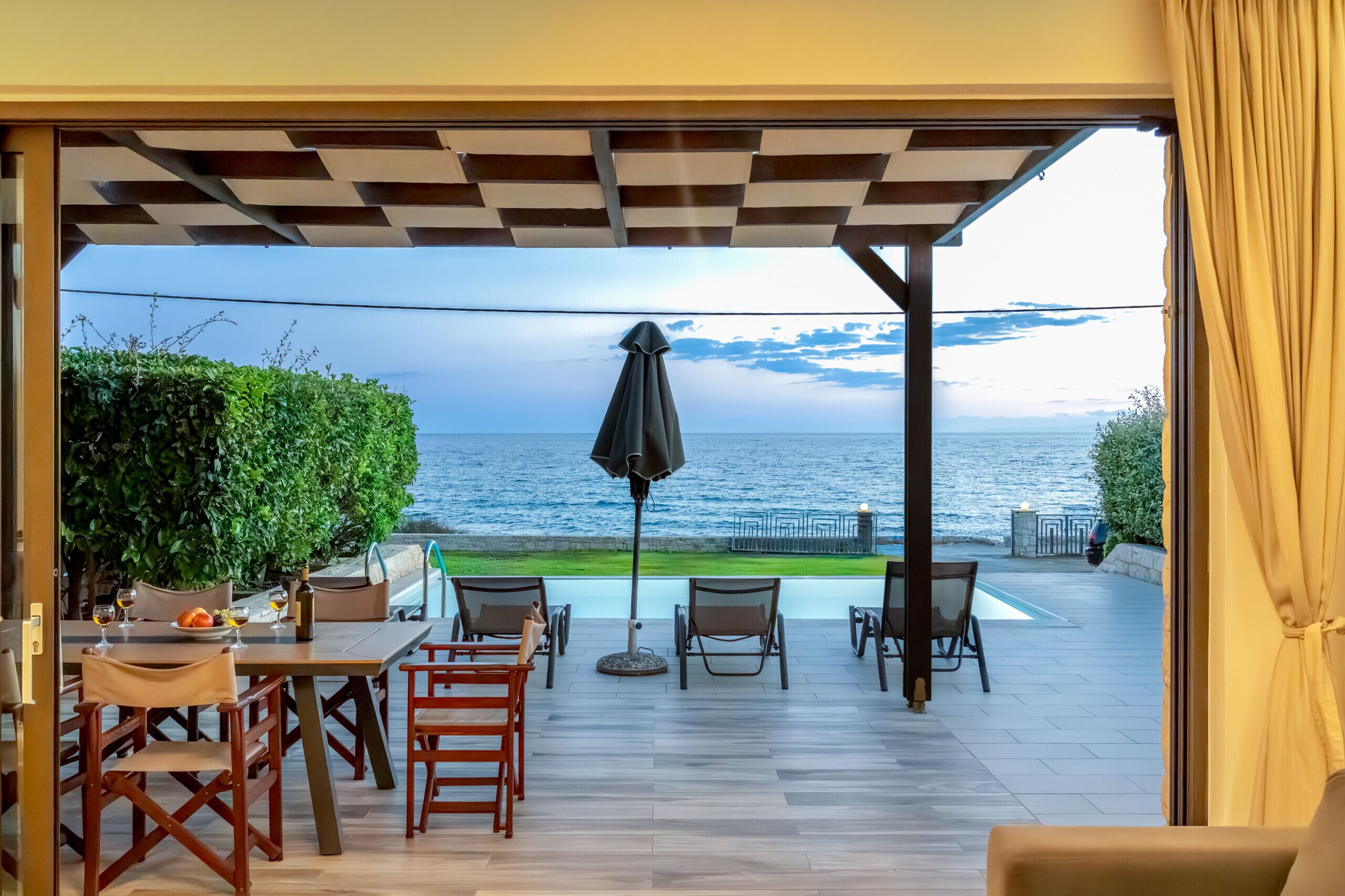 A terrace with a view of the sea, a table set for dining, and outdoor seating.