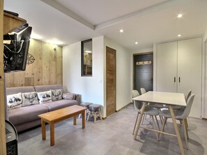A modern living room with a sofa, a wooden coffee table, and a dining table with chairs. - Beautiful renovated apartment 2 rooms cabin, 4-5 pax, station view, Wifi (La Plagne 1800)
