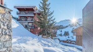 Un complejo turístico en la montaña cubierto de nieve, con un edificio de piedra y una construcción de madera.