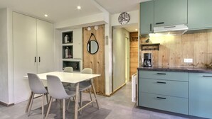 Una cocina moderna con armarios azul verdoso, una cafetera y una pared decorativa de madera.