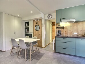 A modern kitchen with teal cabinets, a coffee maker, and a wooden accent wall. - Beautiful renovated apartment 2 rooms cabin, 4-5 pax, station view, Wifi (La Plagne 1800)