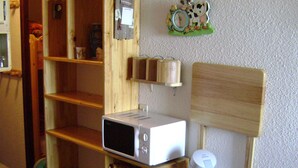 Una cuina amb microones, torradora i cafetera damunt prestatges de fusta.