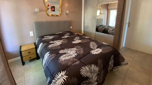 Une chambre à coucher comprenant un lit, une table de chevet, un miroir et une armoire.