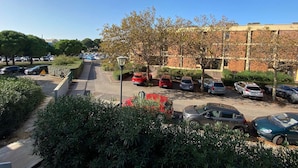 Un parking où sont garées plusieurs voitures, un bâtiment aux murs en briques et des arbres aux feuilles d’automne.