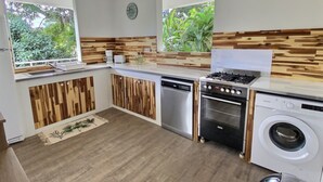 Eine moderne Küche mit Holzelementen, einem Geschirrspüler, einem Herd und einer Waschmaschine.