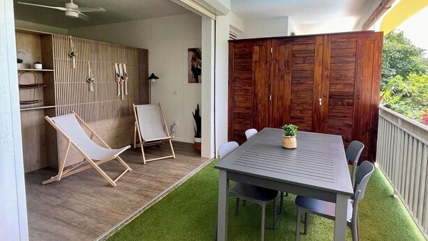 Eine Terrasse mit Tisch, Stühlen und einem Deckenventilator, außerdem eine Holzverkleidung.