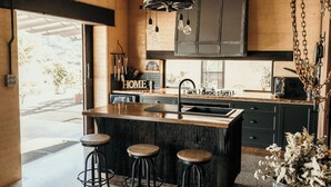 A modern kitchen with a large island, bar stools, and a hanging light fixture. - Mayan Farm Villas (Kin Kin)