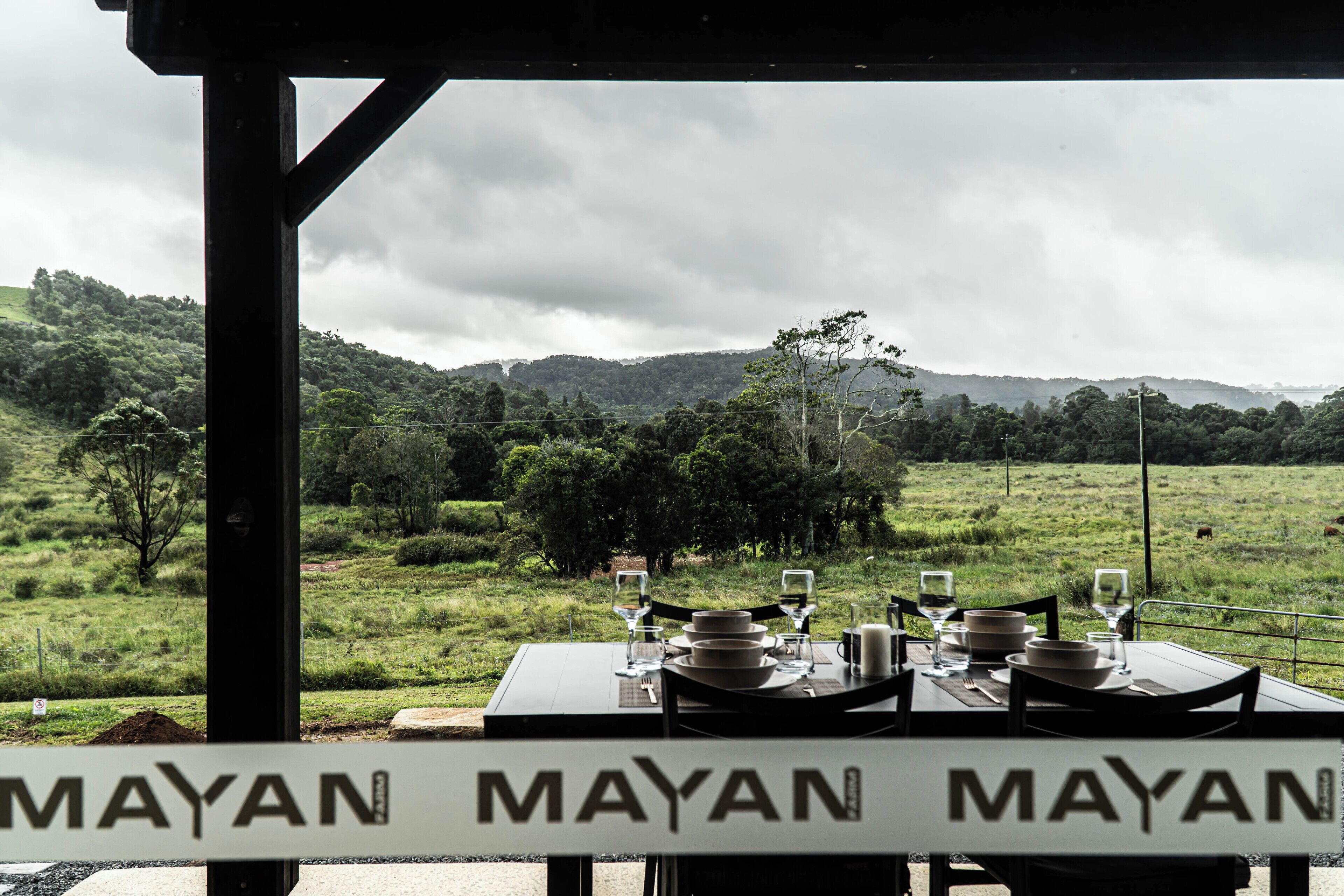 Mesa lista para comer con vista a un campo y colinas al fondo.