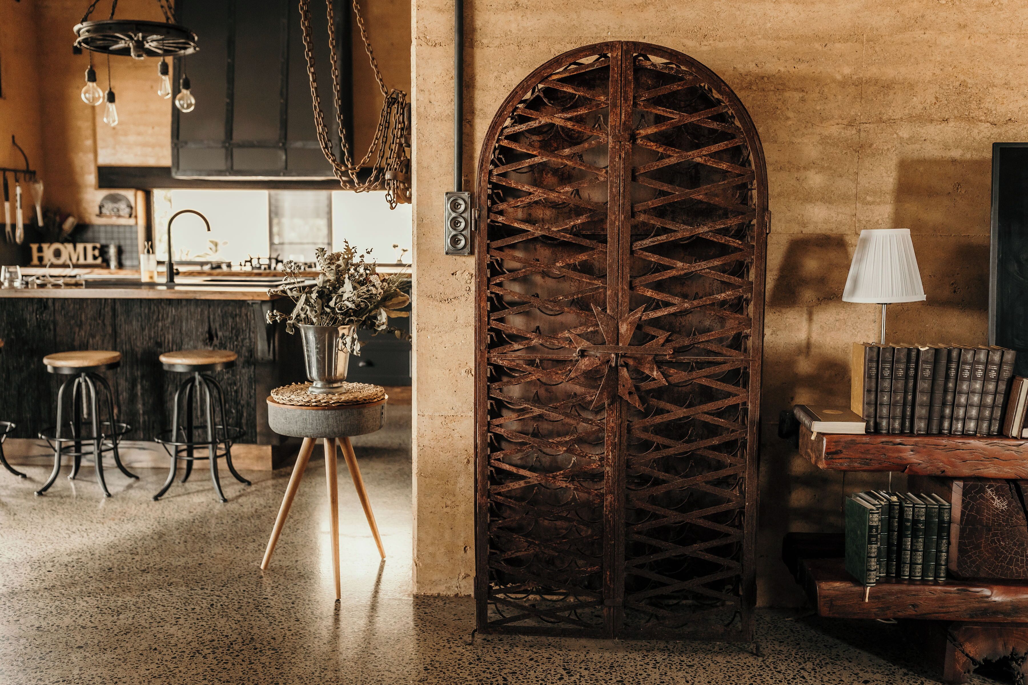 A rustic interior with a wooden door, bar stools, a table with books, and a hanging light fixture.