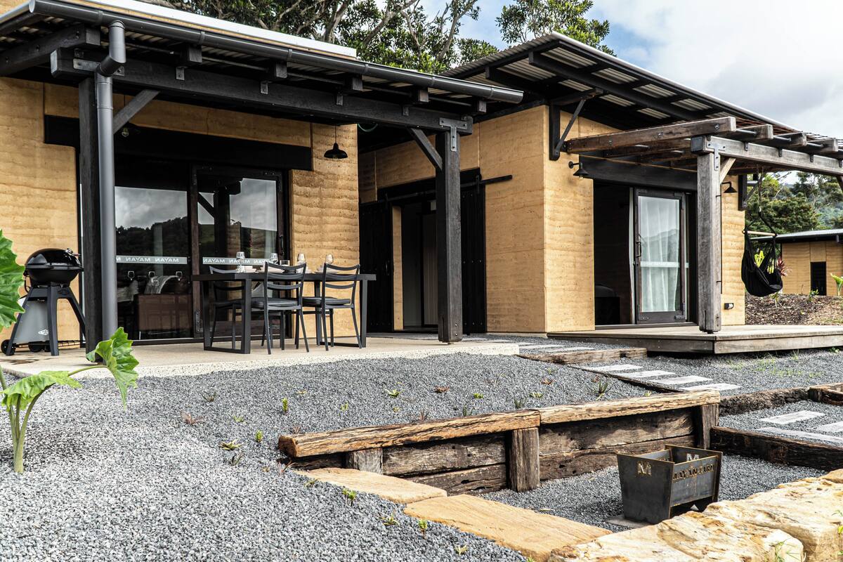 A modern building with a patio area featuring a table and chairs, a grill, and a covered seating area.