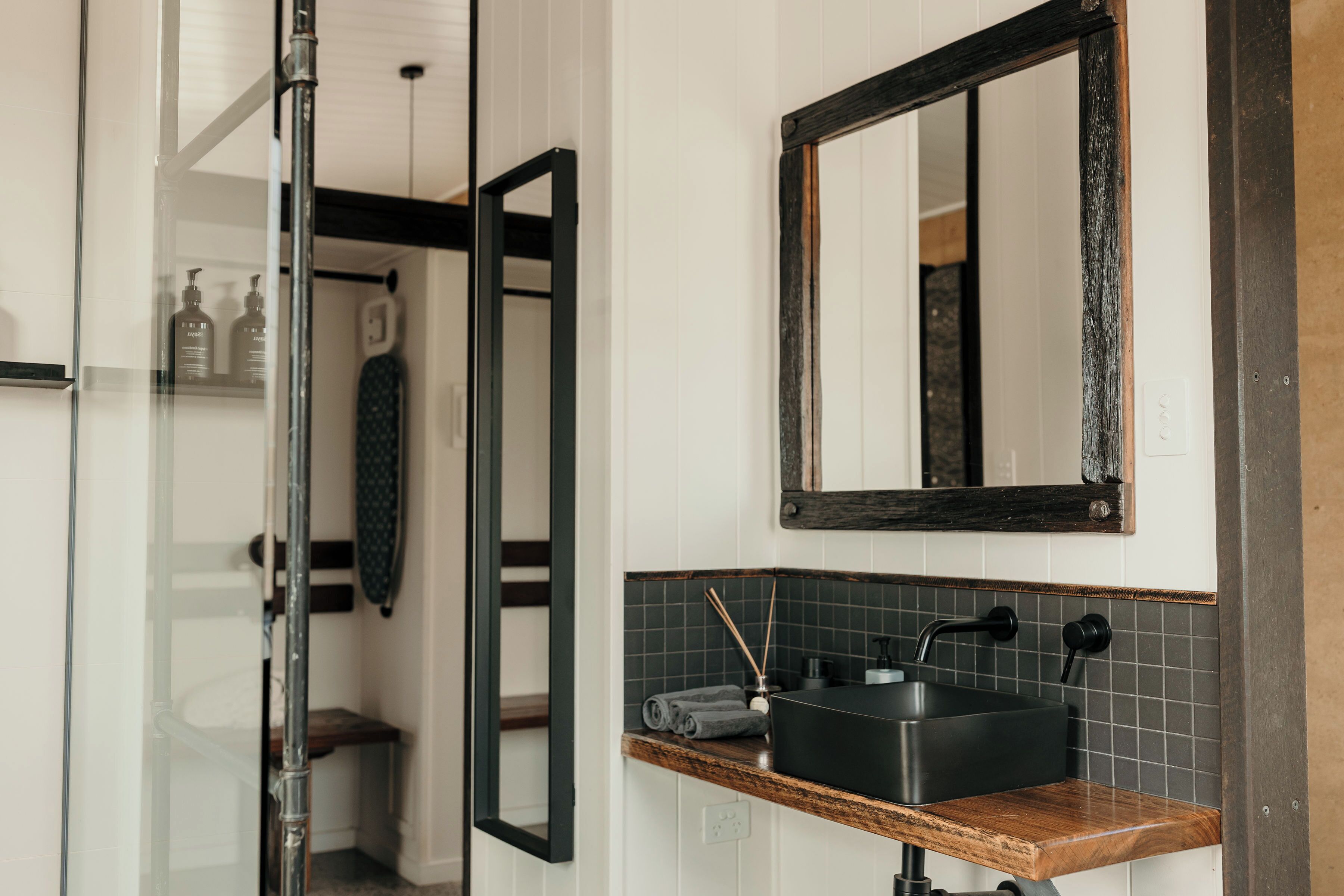 Un baño con un mueble de tocador de madera, un lavamanos negro y un espejo.