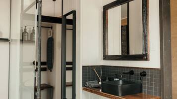 Un baño con un mueble de tocador de madera, un lavamanos negro y un espejo.