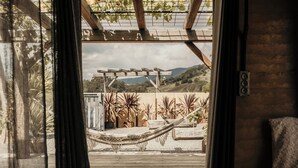 A hammock under a wooden pergola with a view of a garden and hills. - Mayan Farm Villas (Kin Kin)