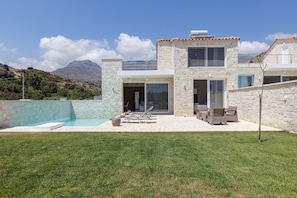 Ein modernes Haus mit Schwimmbad, Sitzgelegenheit im Freien und Blick auf die Berge.