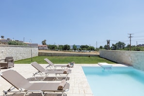 Ein Poolbereich mit Liegestühlen und einer Steinmauer.