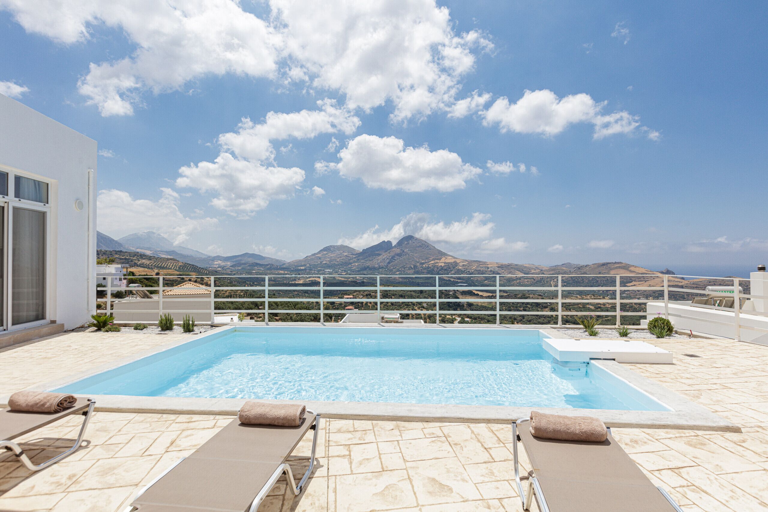 A rooftop pool with lounge chairs and a view of mountains.