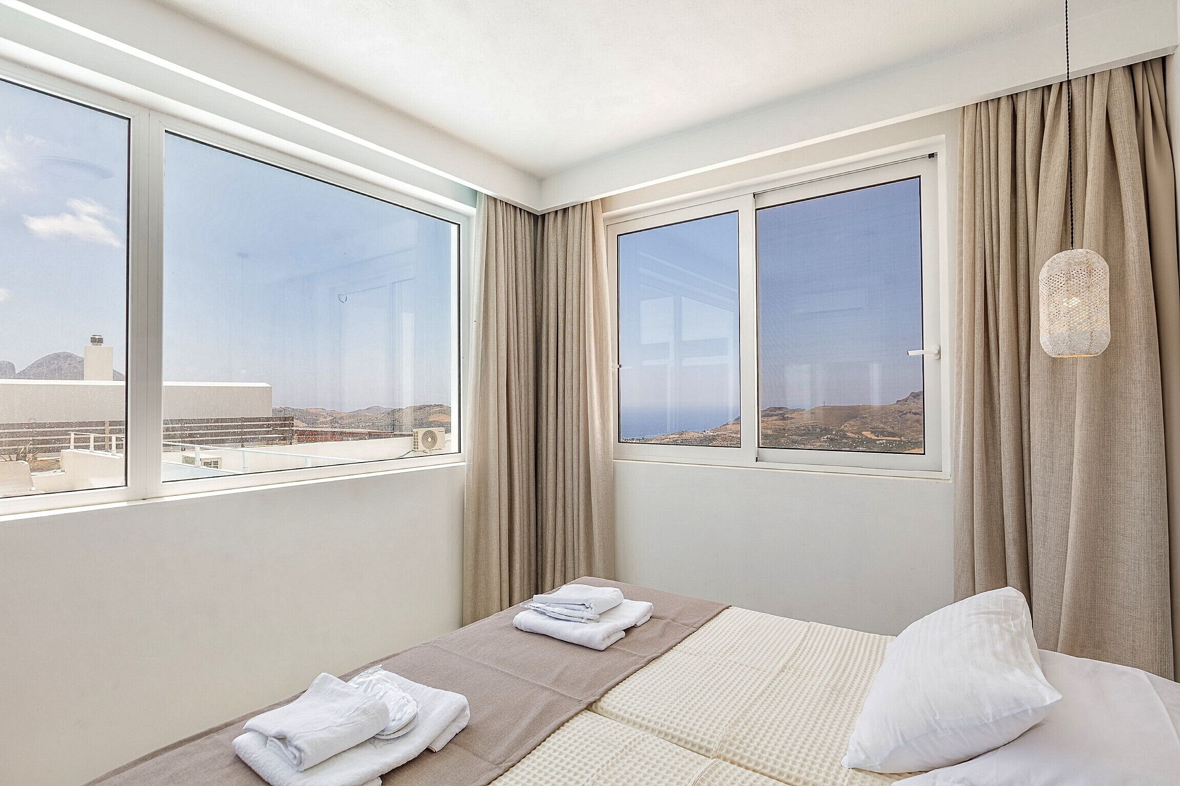 Une chambre d’hôtel avec un lit, une fenêtre avec des rideaux et une vue sur le paysage.