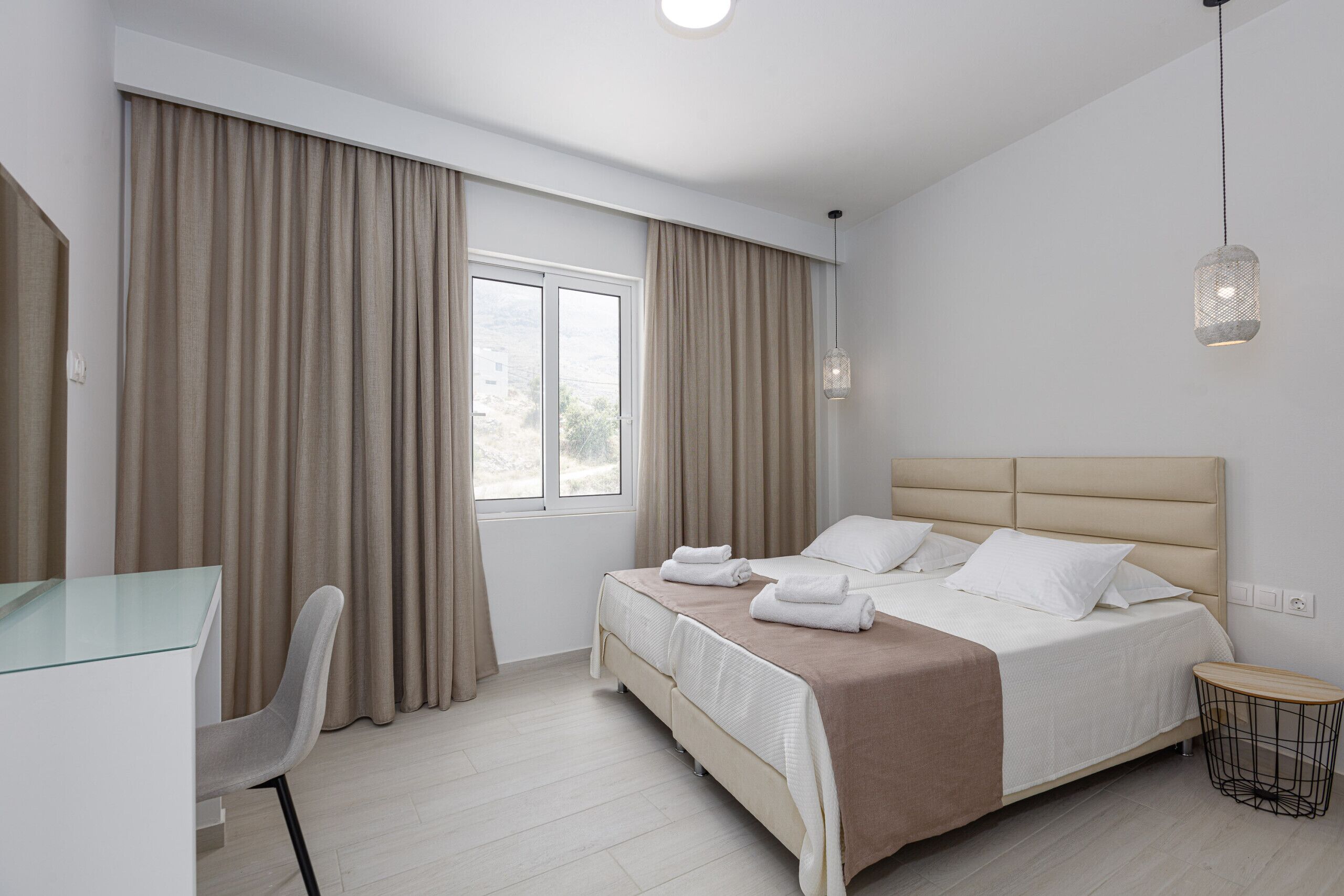 A modern hotel room with a bed, a desk, and a chair.