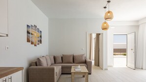 A modern living room with a sofa, a coffee table, and a view of the outdoors. - Petres Villas (Agios Vasileios)