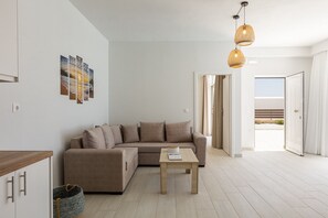 A modern living room with a sofa, a coffee table, and a view of the outdoors. - Petres Villas (Agios Vasileios)