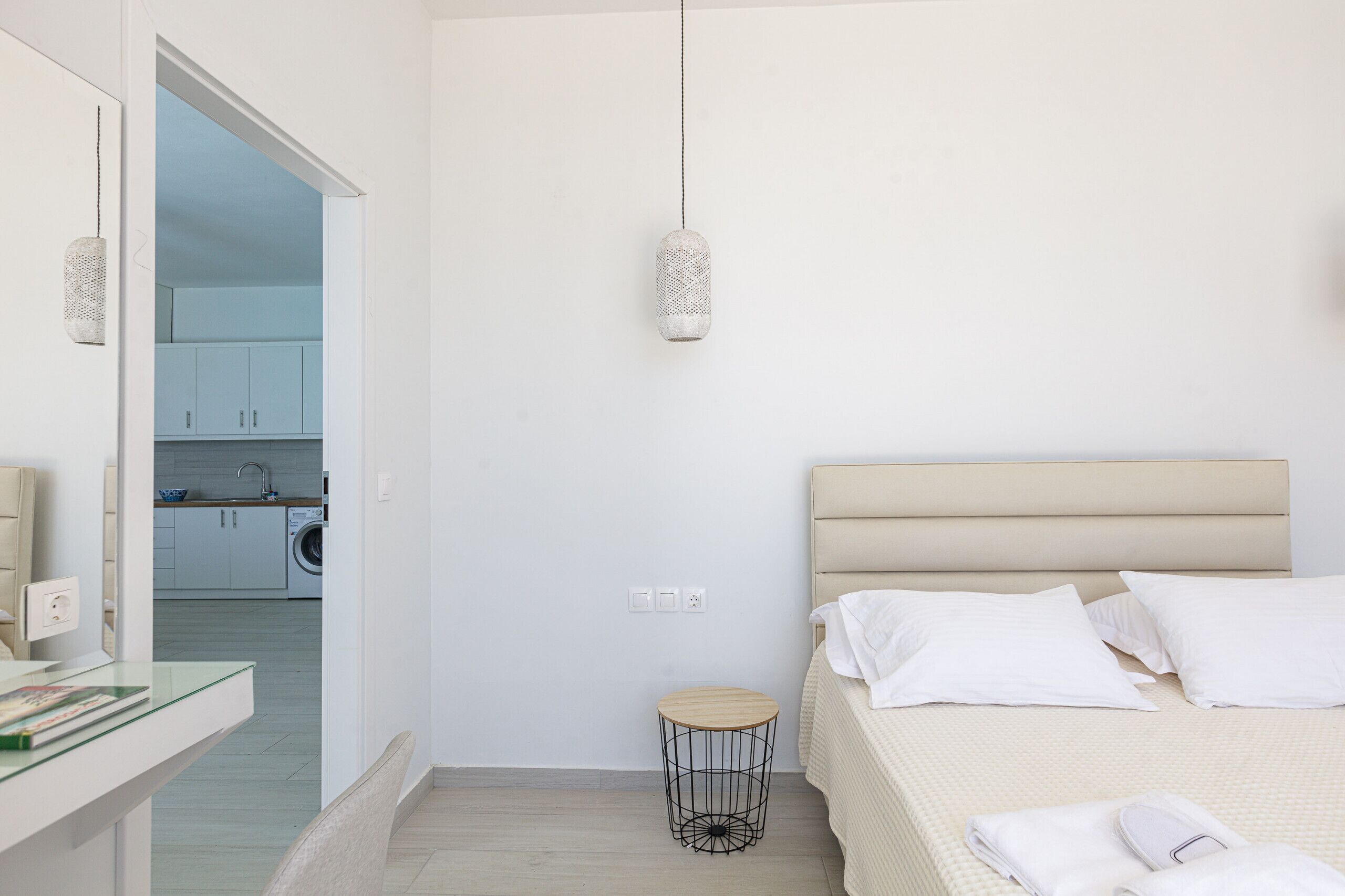 Een slaapkamer met een bed, nachtkastje en een hanglamp.