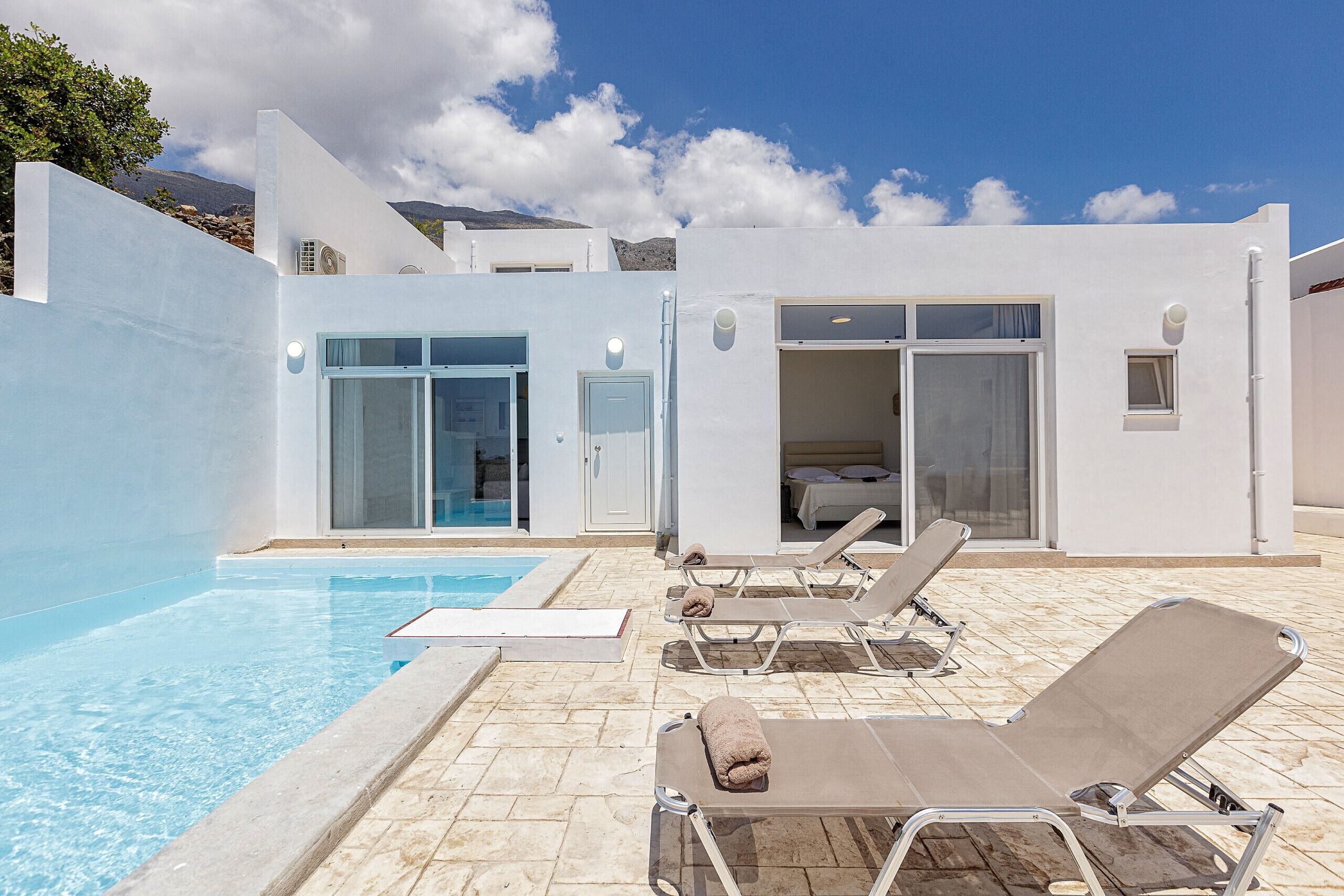 A modern pool area with lounge chairs and a clear sky.