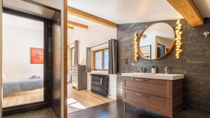 A modern bathroom with a large mirror, wooden beams, and a radiator. - Chalet in the heart of the Pyrenees, at the foot of the slopes (Saint-Lary-Soulan)