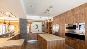A modern kitchen with wooden cabinetry, stainless steel appliances, and pendant lighting. - Chalet in the heart of the Pyrenees, at the foot of the slopes (Saint-Lary-Soulan)