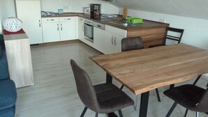 Una cocina compacta con armarios blancos, una mesa de comedor de madera y dos sillas.