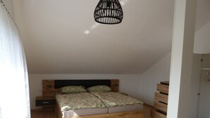 Un dormitorio con cama de madera, lámpara colgante y suelo de madera.