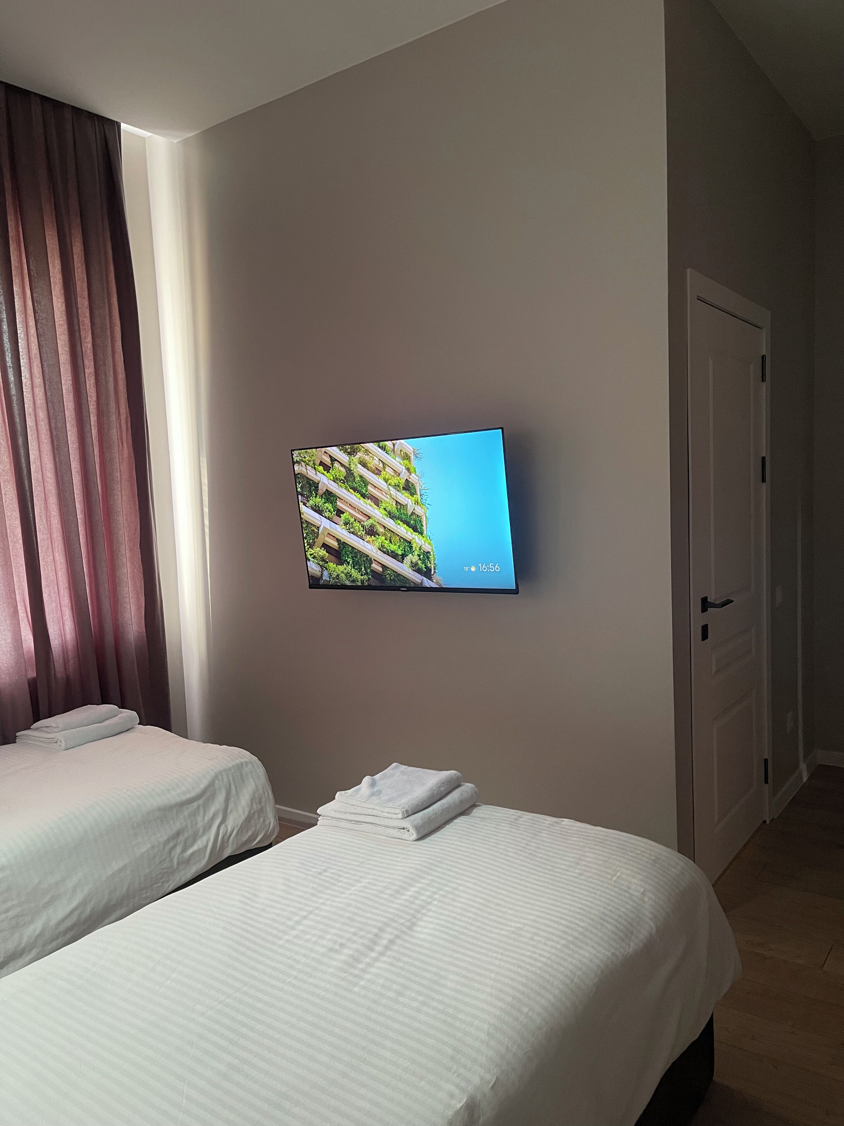 Una habitación de hotel con dos camas, un televisor en la pared y una puerta.