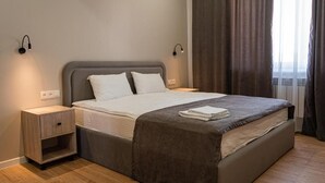 A modern hotel room with a large bed, bedside tables, and a window with curtains. - BnB Hotel Shymkent (Shymkent)