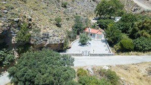 A small building with a red roof, surrounded by trees and rocky terrain. - Sunset Maisonettes (Agios Vasileios)