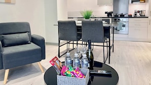 Una cocina moderna con comedor, que incluye una mesa con sillas, un control remoto y una cesta de aperitivos.