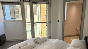 Una habitación de hotel con cama, baño y vistas al exterior.