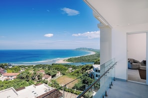 A balcony with a view of the ocean and a beach. - Brand New Ocean View Condo with Infinity Pool (Playa Tamarindo)