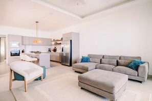 A modern living room with a grey sectional sofa, a white armchair, and a matching ottoman.