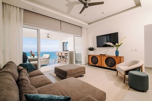 A modern living room with a sofa, ottoman, and a TV mounted on the wall.