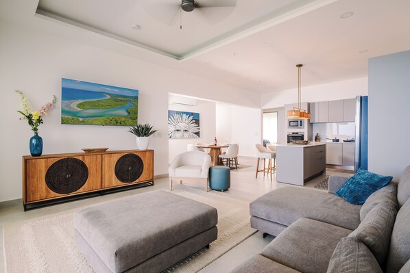 A modern living room with a sofa, ottoman, and a cabinet with decorative panels.