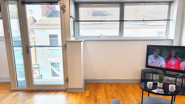 Una sala de estar con un televisor, una mesa de centro con dos tazas y un sofá.