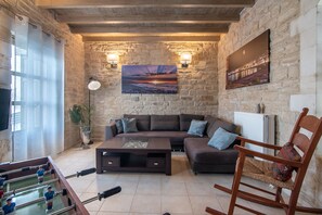 A cozy living room with a stone wall, a sofa, a coffee table, a foosball table, and a chair. - Alexandros 3 Villa (Rethymno)